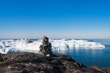Cairn (pile of stones) overlooking icebergs of Sermermiut, Ilulissat, Greenland