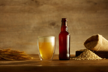 A glass and bottle of beer and wheat in brown background ,  mug of beer for food and drinking...