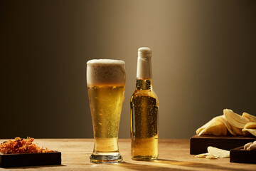 A glass and bottle of beer and fried potatoes spicy chicken floss in grey background ,  mug of beer for food and drinking advertising front view