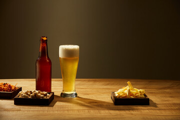 A glass and bottle of beer and fried potatoes spicy chicken floss in grey background ,  mug of beer...