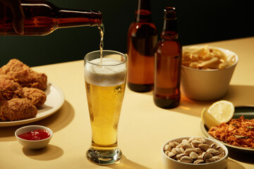 A glass of beer with fried potatoes spicy chicken floss and fried chicken in brown background , mug...