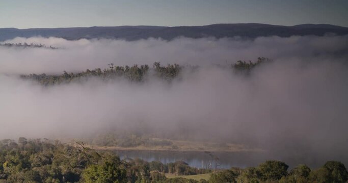 coastal mountain range at sunrise covered by morning mist clouds