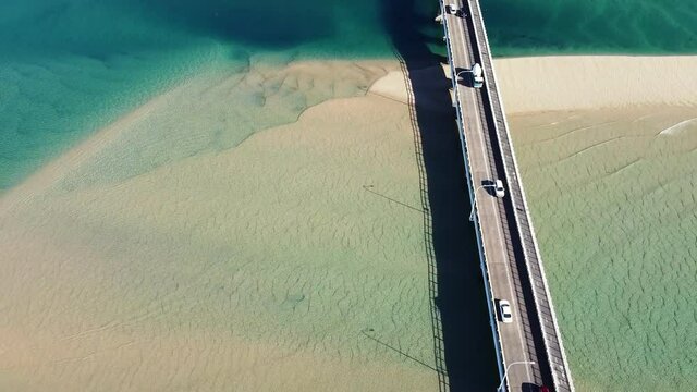 Cars passing over bridge with beautiful blue water below