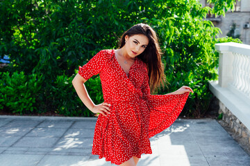 beautiful brunette woman in summer red dress walking outside