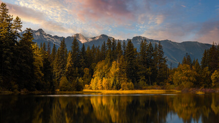 Lake surrounded by greenery and rocky hills during the sunrise in Jasper National Park