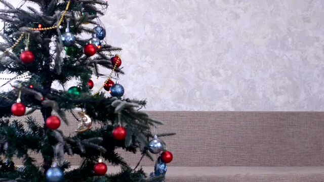 christmas tree background decorated with red balls and garland light at home interior, festive cozy everning no people with copy space text, empty coach in the room.