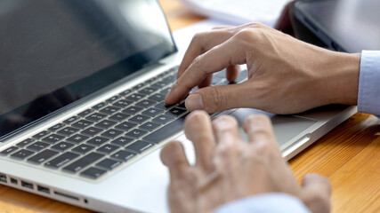 Businessman's hand presses on a laptop keyboard, Using computers to conduct financial transactions because the convenience and speed, World of technology and internet communication.