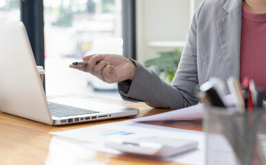 Business professionals are analyzing data using laptops to compute company annual revenue statistics, Earnings Insights Graph, Finance, Accounting, Tax system, Vat, Working in the office.