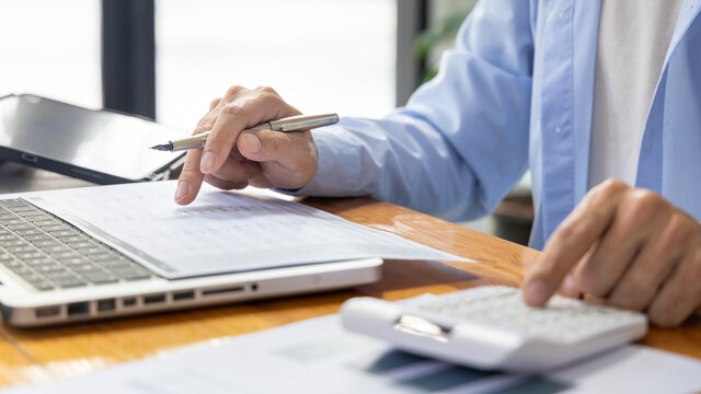 Businessman Presses A Calculator To Calculate Earnings And Analyze Company Earnings In His Private Office, Information In Finance And Accounting, Company Performance And Revenue.