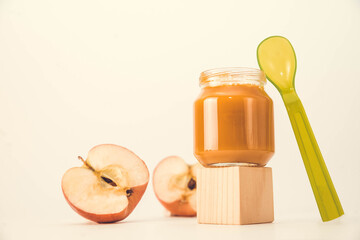baby puree in a transparent glass jar on a white background. fruit baby puree with spoon. jar of baby puree with fruit