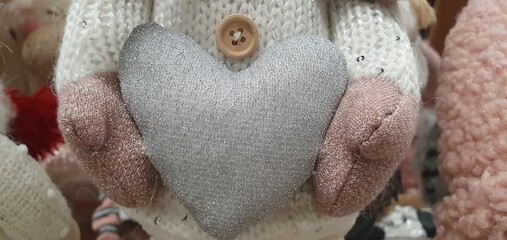 Delicate heart in the hands. Soft gray fabric heart. Toy heart. Valentine's day background.