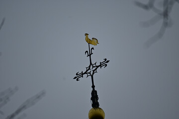 Antique cross on the top of a church on a gloomy day