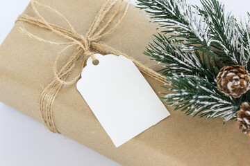 Christmas and New Years background close-up. Gift box wrapped in kraft paper with jute cord. Decorated with a label and a branch with cones