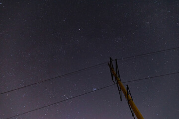 power line on the background of the night starry sky constellation pleiades