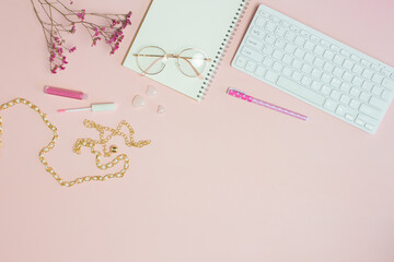 Woman working items with keyboard, notebook, lip, and glasses over the pink background. 