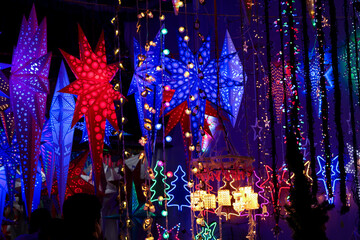 Christmas lights lightning paper lantern star hanging in Christmas market in Kerala India lots of bright colorful stars night photo. Indian winter holidays shopping for x-mas  New Year celebration
