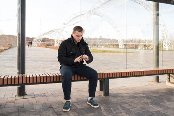 man sitting on bus stop and waiting for public transport