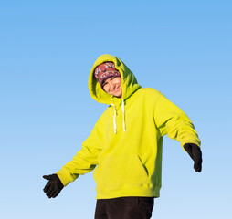 A young girl in a green hoody in nature against the sky invites to follow her