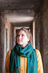 Portrait of a girl in a yellow jacket and a green scarf in an abandoned building