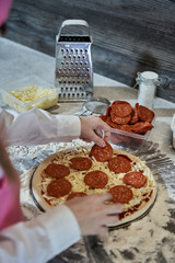 little young pretty girl is cooking a pizza on a wood table