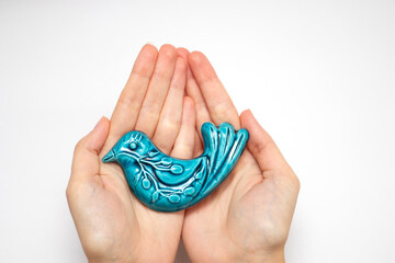 A figurine of a blue ceramic bird in hand. The blue bird is a symbol of happiness