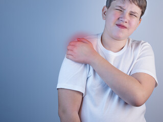 A young man suffering from shoulder pain. Concept disease. Pain in the shoulder joint, muscle pain....