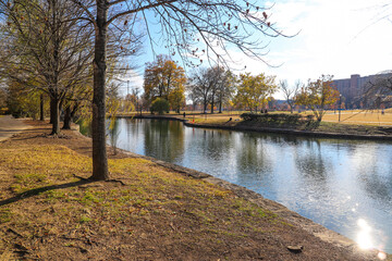 a gorgeous shot of the still blue lake in the park surrounded by gorgeous lush green and red and...