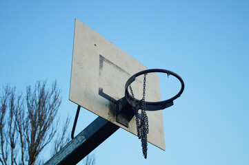A worn basketball hoop in a public recreational area.