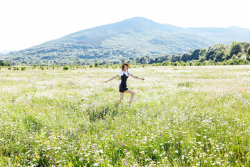 Fototapeta na wymiar beautiful woman in a hat in a field of chamomile flowers