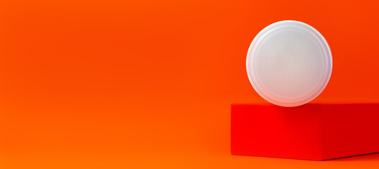 White blank cream jar mockup on geometrical podium orange background banner copy space. Skincare product unbranded plastic package. Natural eco-friendly anti aging skin cosmetic facial moisturizer SPA