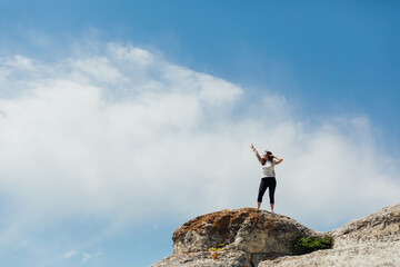 beautiful female traveler standing on top of a mountain on a hike