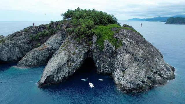 Aerial view of birds flying in front of the Santana island, in Sao Tome - pull back, drone shot