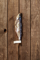 Salted air-dried Baltic herring with label on tail on rough wooden background