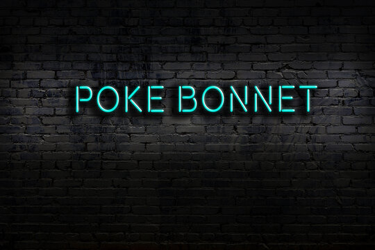 Night view of neon sign on brick wall with inscription poke bonnet