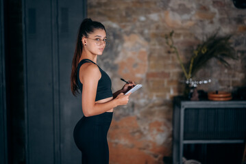 Obraz premium Young women standing writing down something into the notebook.