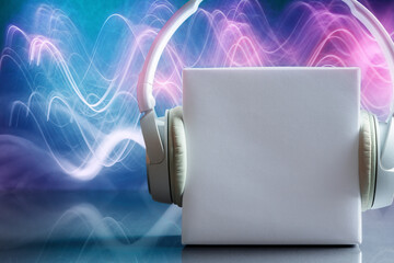 Fototapeta na wymiar White blank box with headphones over abstract wave-shaped lights