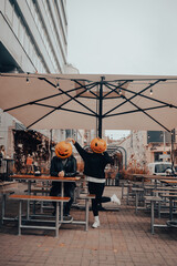 Guy and girl with pumpkin heads in a street cafe