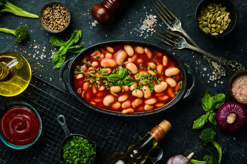 Baked beans in tomato sauce on a black stone plate. Top view. On a stone background.