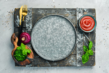 Cooking background: metal plate, vegetables and spices. Top view. On a stone background.