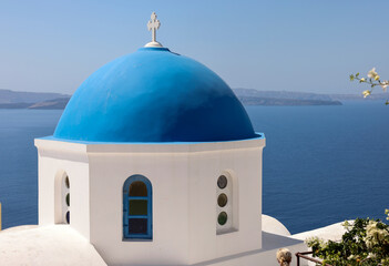 Fototapeta na wymiar View from viewpoint of Oia village with blue dome of greek orthodox Christian church. Santorini, Greece