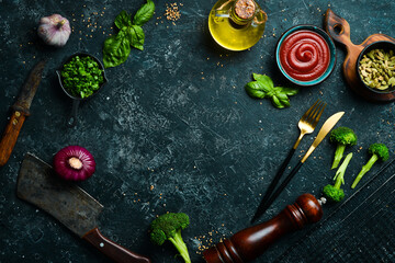 Black stone cooking background. Spices and vegetables. Top view. Free space for your text.