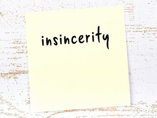 Yellow sticky note on wooden wall with handwritten word insincerity - obrazy, fototapety, plakaty