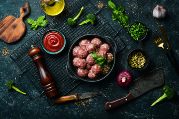 Fresh raw beef meatballs with spices in a pan. Top view. On a stone background.