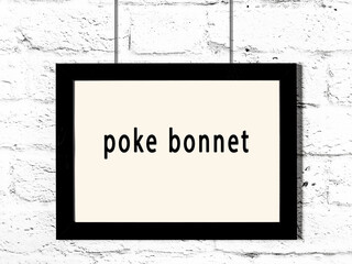 Black frame hanging on white brick wall with inscription poke bonnet