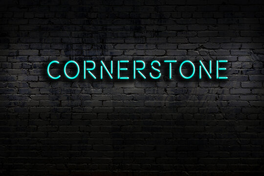 Night view of neon sign on brick wall with inscription cornerstone