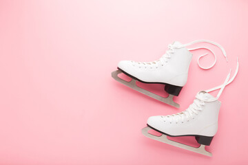 White female figure skates on light pink table background. Pastel color. Sport accessories for...