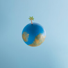 Painted foam ball, palm tree on top. Minimal creative concept, globe in space, tropic island idea. Saved place on a map. 