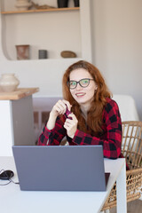 young red-haired girl makes purchases in the online store using a credit card