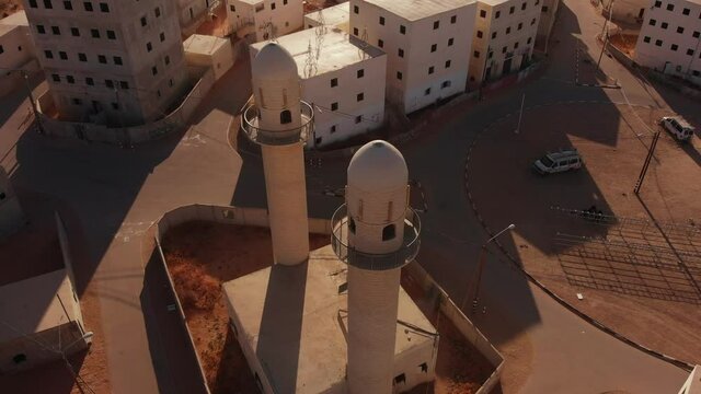 aerial shot of two mosques next to the main squere in an old empty city in the desert in palestine near Gaza at sunset.