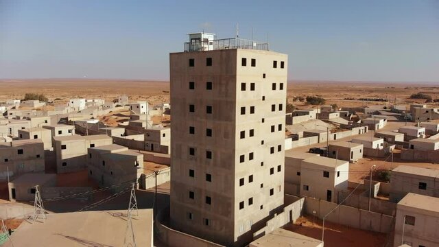 aerial view of big building in an old empty city at palestine near gaza in the desert while camera moves forward revealing the rest of the city.
